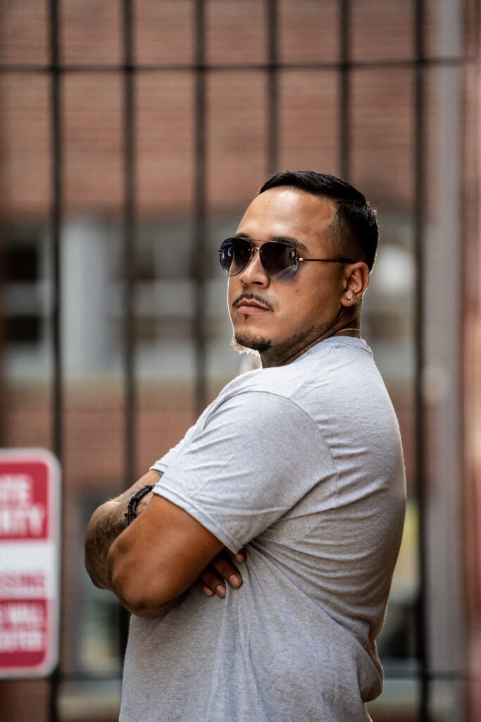 Man in sunglasses leaning back outdoors, representing fatherhood, legacy, and men’s self improvement as a present, consistent leader at home.