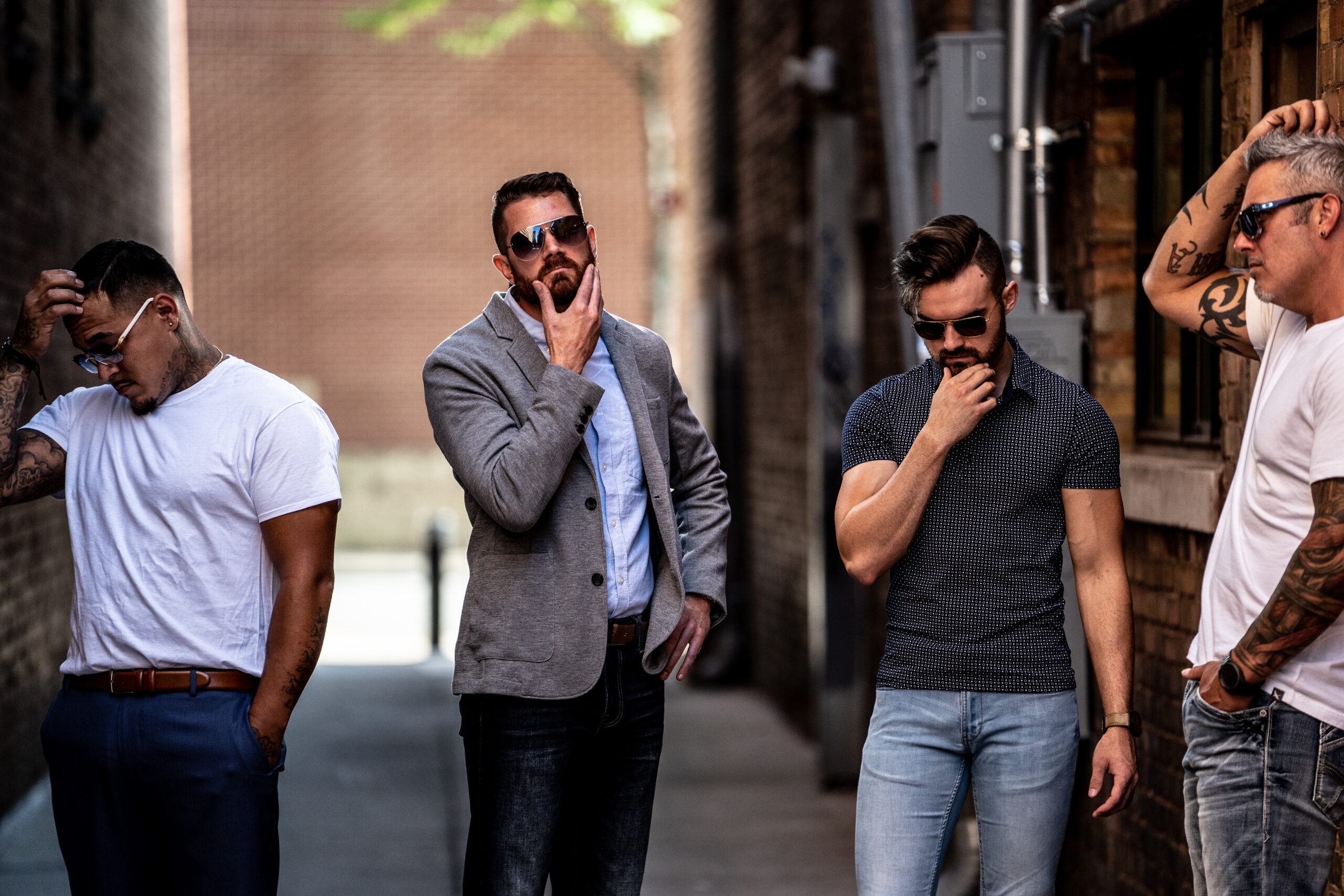 Four stylish men standing in an urban alley, each deep in thought, representing men’s self improvement and modern brotherhood.